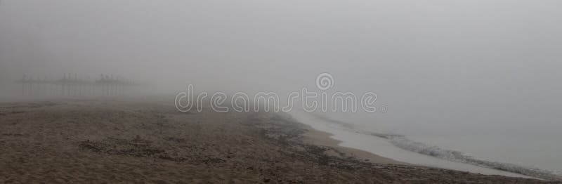 Unusual Fog in el arenal beach in mallorca wide. Rare and unusual heavy fog over the coast with sun umbrellas and shoreline of El Arenal beach touristic area royalty free stock photos