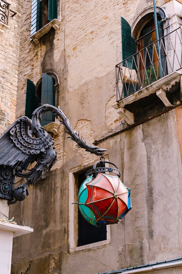 An unusual street lamp in the shape of The Maforio Dragon on the corner of the building, with a ball of three umbrellas. Blue, green and red, on the streets royalty free stock image